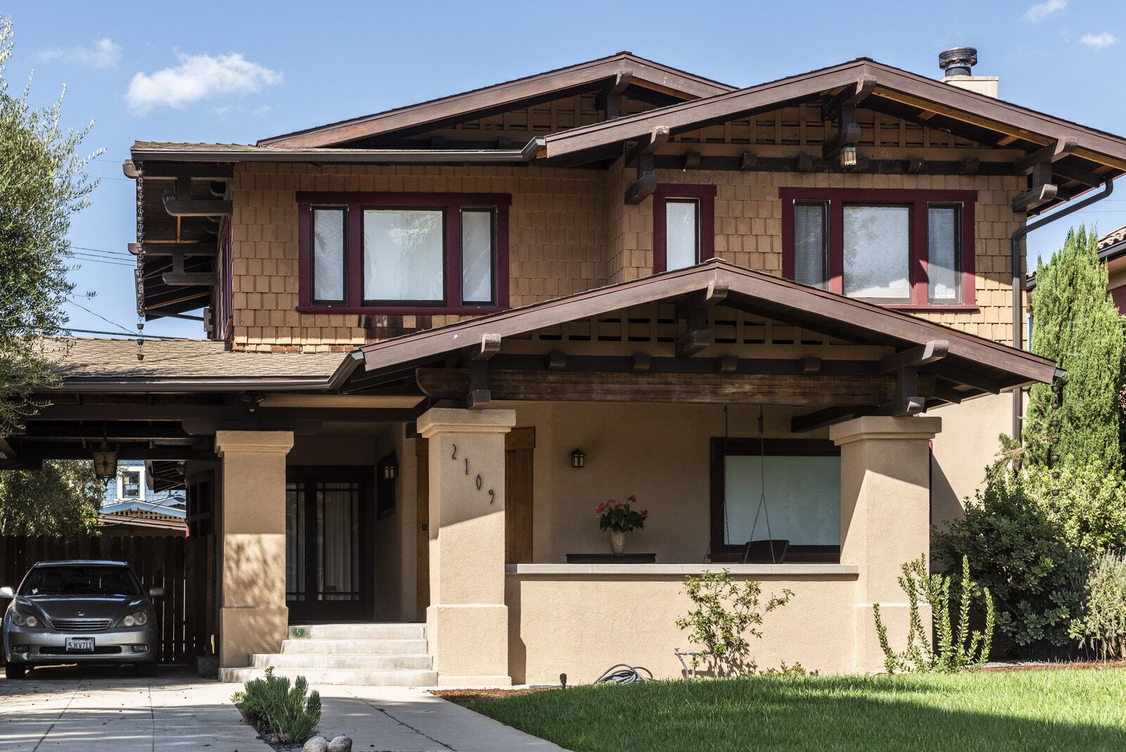 A brown-shingled two-story Craftsman with a deep front porch and wide eaves